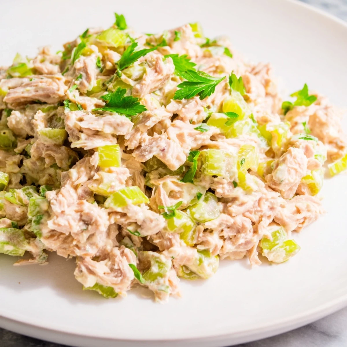 Spicy Zesty Tuna Salad served in a crisp lettuce cup, garnished with chopped parsley and a bright lemon wedge for a zesty kick.