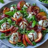 Juicy peach and burrata salad with prosciutto, drizzled with balsamic glaze.