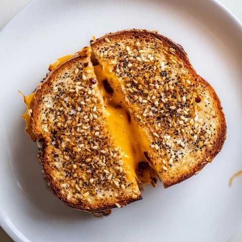 Everything Bagel Grilled Cheese with melted cheddar oozing out on golden-brown bread.