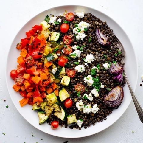 A close-up of a vibrant Black Lentil Salad with Roasted Vegetables, featuring glossy black lentils mixed with caramelized bell peppers and zucchini.
