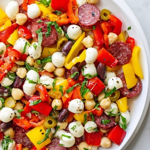 A vibrant bowl of chopped antipasto salad with chickpeas, mozzarella pearls, and fresh herbs for a satisfying gluten-free lunch.  