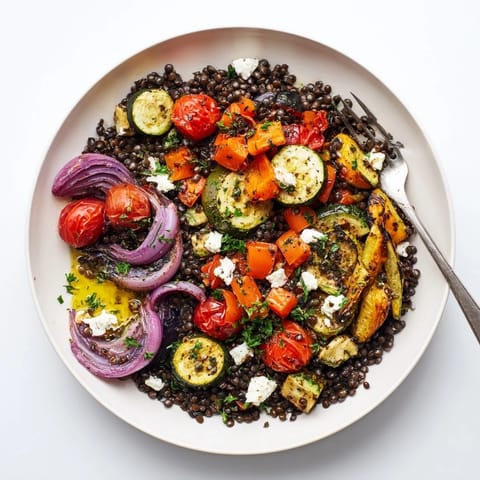 A healthy Black Lentil Salad with Roasted Vegetables served in a white bowl, garnished with fresh parsley and crumbled feta cheese.