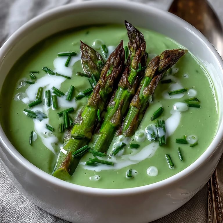 Fresh Asparagus Soup served warm in a rustic bowl, topped with blanched tips and a swirl of cream.