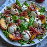 Creamy burrata salad with sweet peaches and crispy prosciutto, ideal for summer.